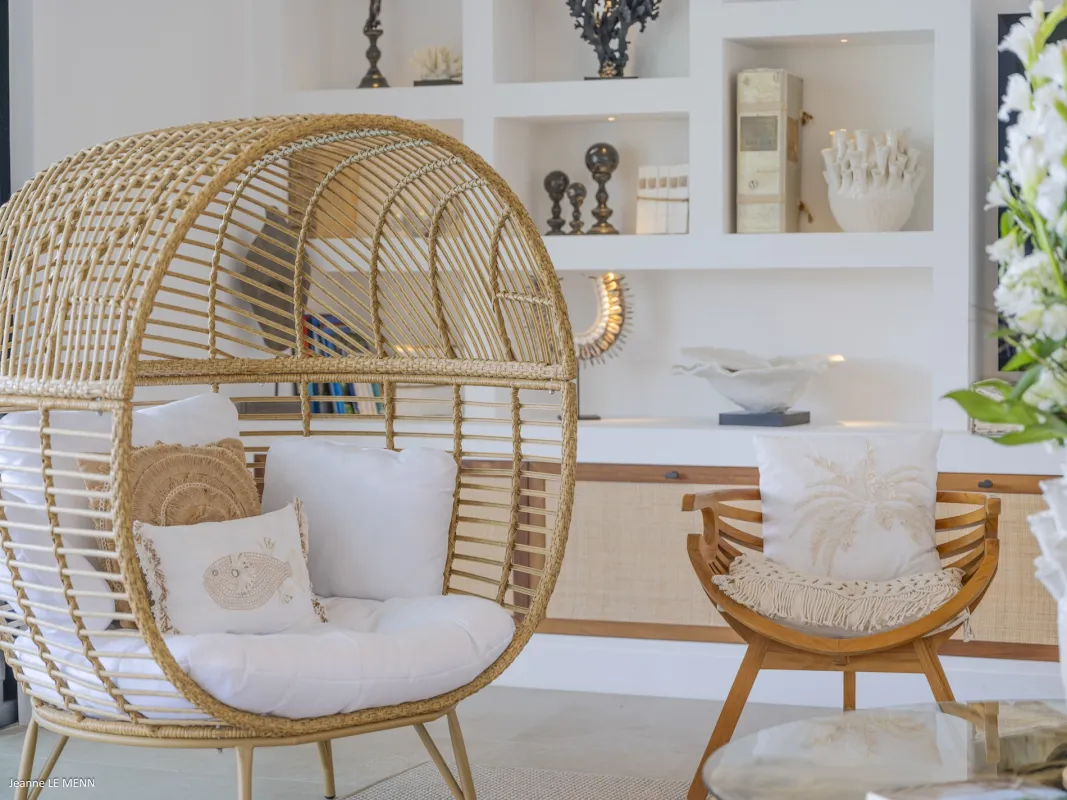 Villa Abaca: Woven globe chair and wooden armchair in a living area with built-in shelves