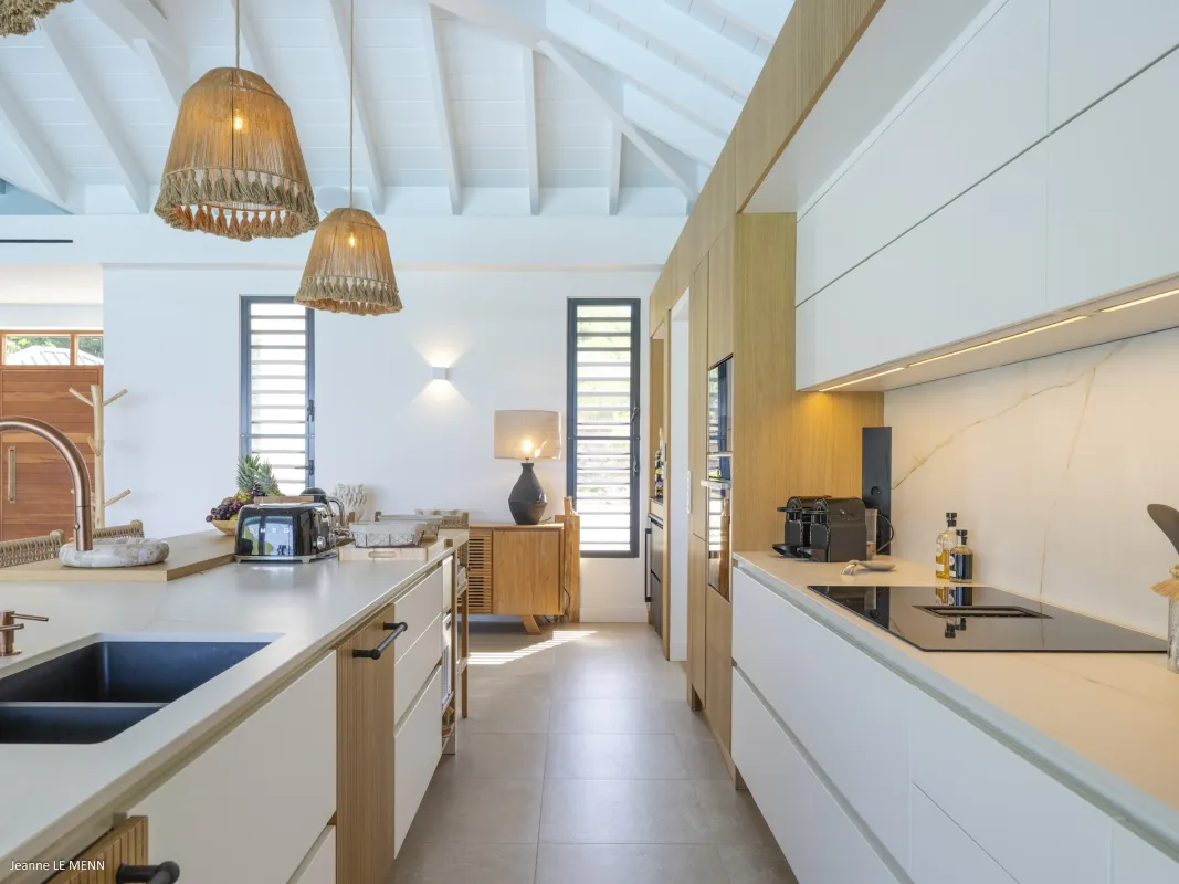 Villa Abaca: Modern kitchen with large central island, white cabinetry, and woven pendant lights