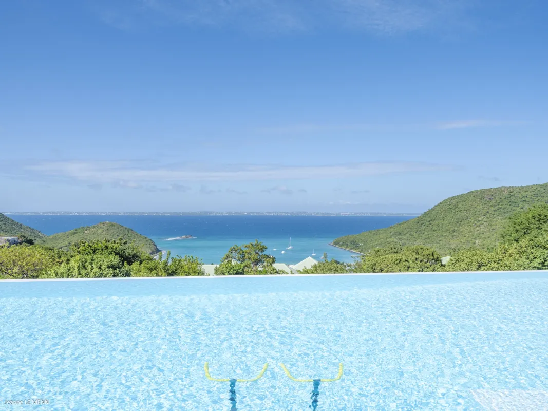 Villa Abaca: Infinity pool with submerged exercise bikes overlooking an ocean bay