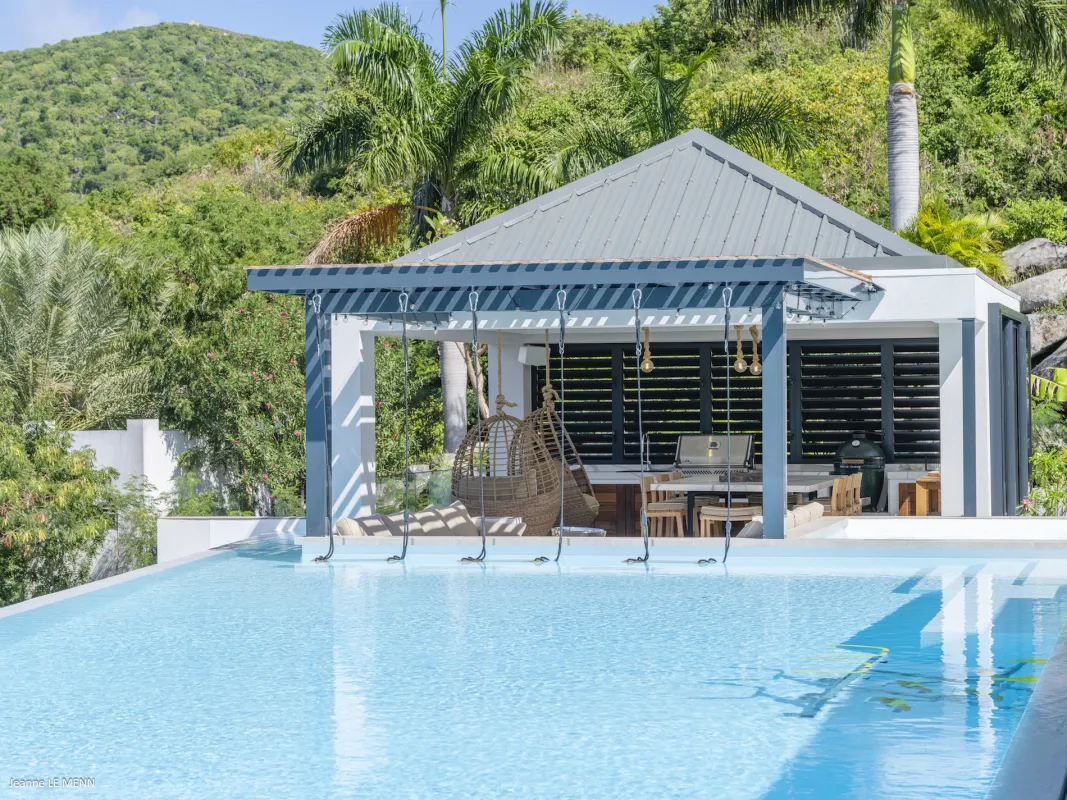 Villa Abaca: Swimming pool beside a covered outdoor pavilion with swing chairs and lush hillside greenery
