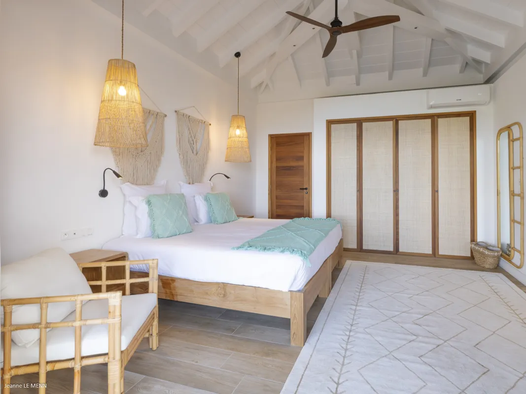Villa Abaca: Spacious bedroom with a wooden bed, vaulted ceiling, and woven pendant lights