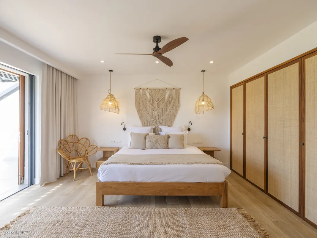 Villa Abaca: Bright bedroom featuring a wooden bed, macrame wall hanging, and woven pendant lights