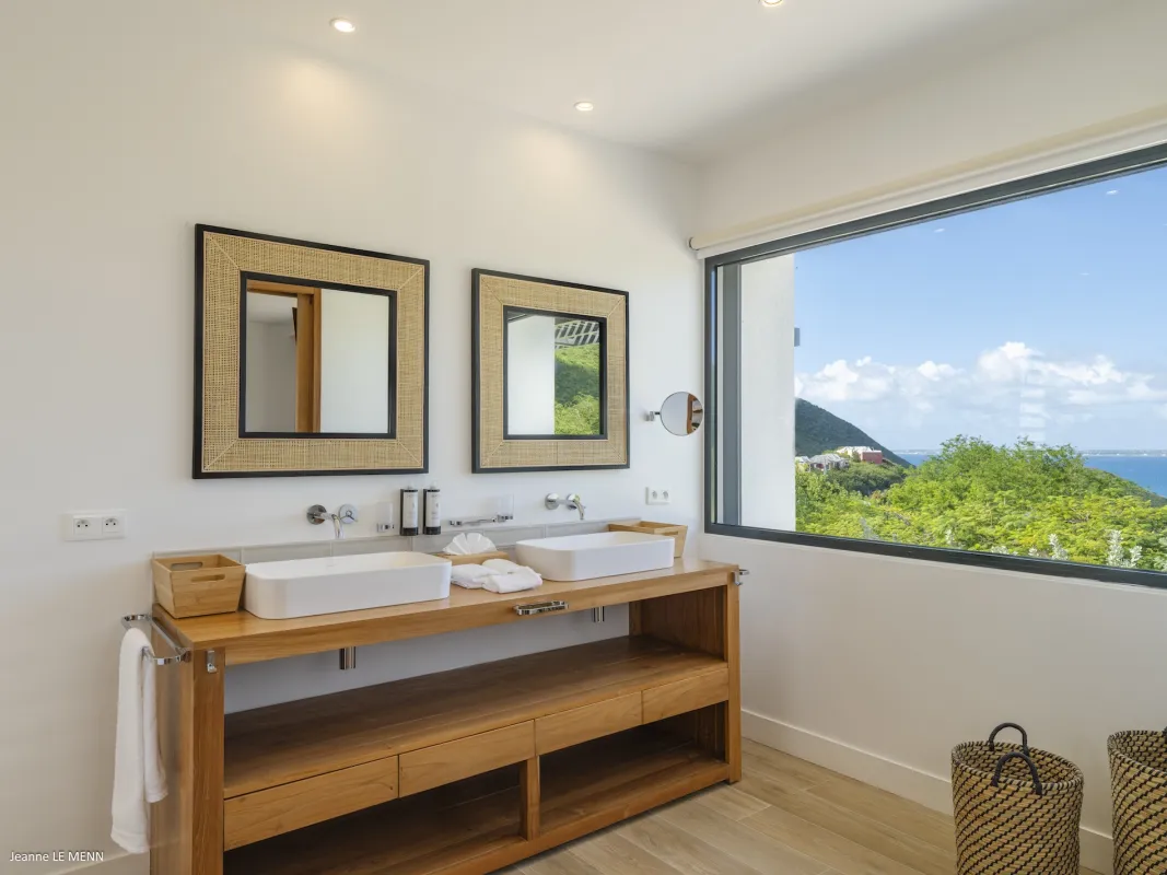 Villa Abaca: Bathroom double sink vanity with framed mirrors and large window overlooking lush hills and sea