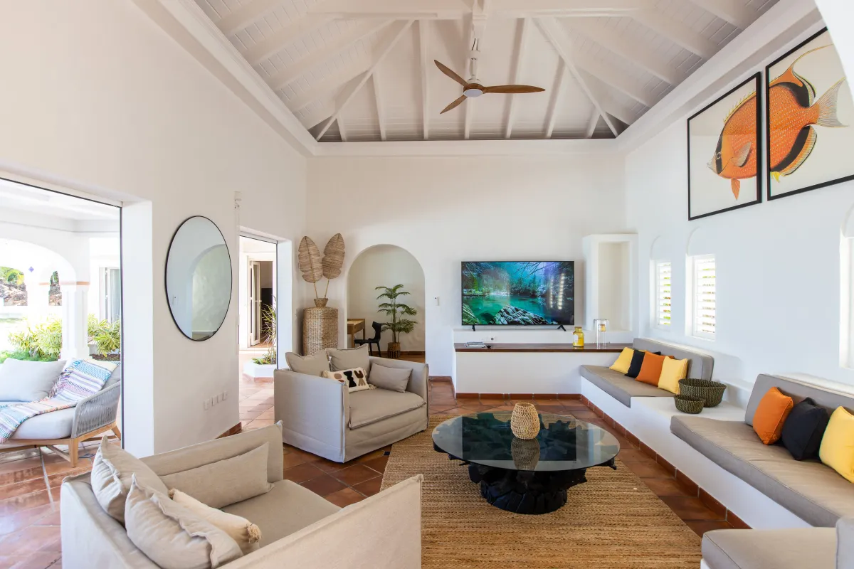 Villa Agama: Bright living room with vaulted ceiling, cushioned seating, glass coffee table, and television