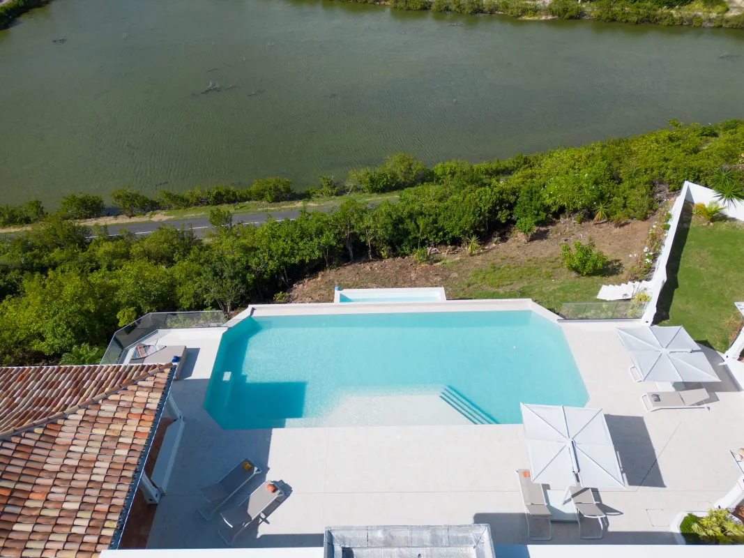 Villa Agama: High-angle view of an outdoor swimming pool terrace overlooking water and lush greenery