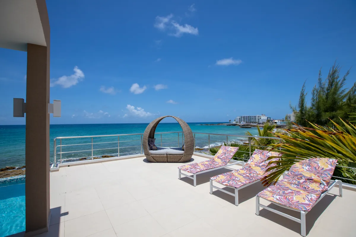 Villa Alma: Sun loungers and a covered daybed on a tiled terrace overlooking the ocean