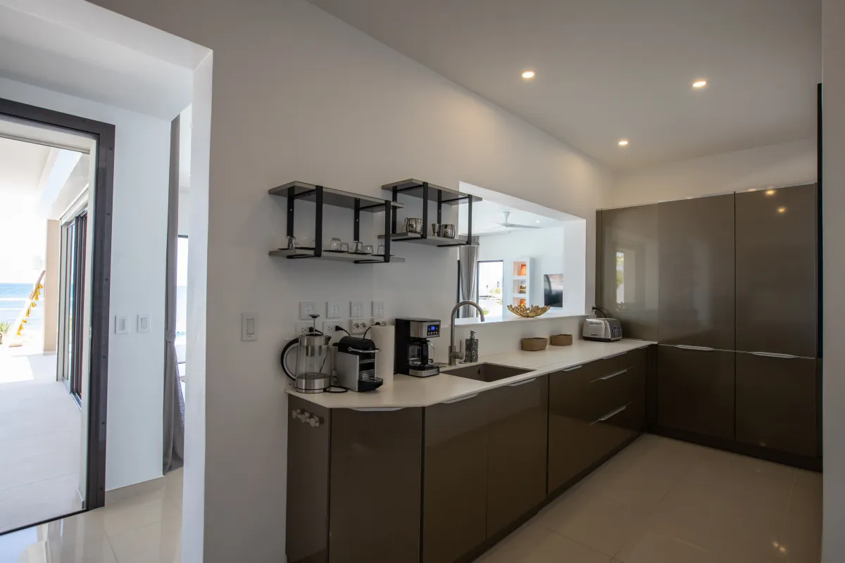 Villa Alma: Modern kitchen with sleek taupe cabinetry, white countertops, and small appliances