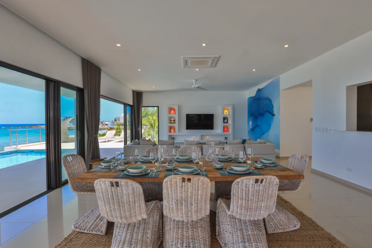 Villa Alma: Dining table set for a meal beside glass doors opening to the pool and ocean