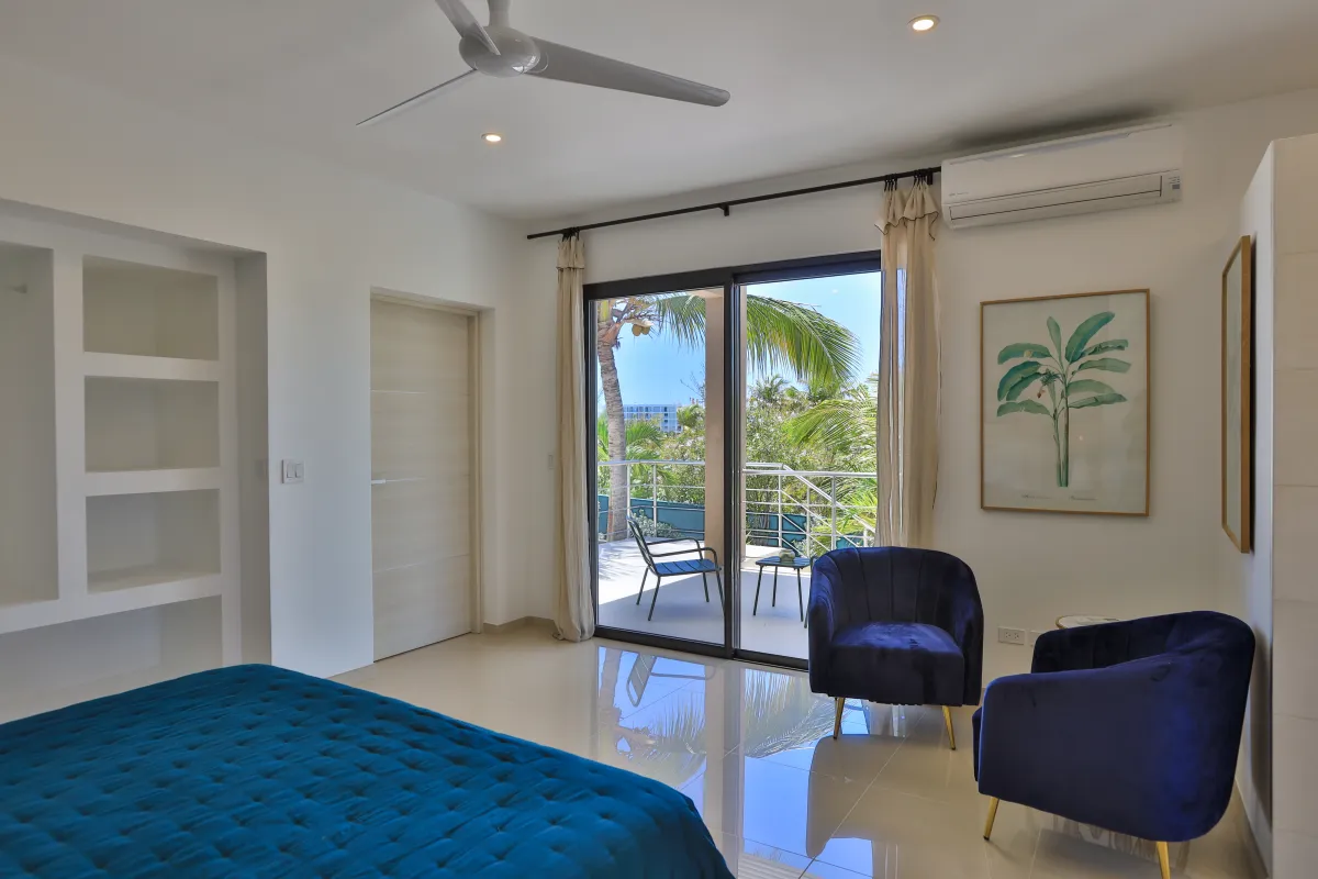 Villa Alma: Bedroom with blue armchairs and sliding glass doors opening to a private balcony