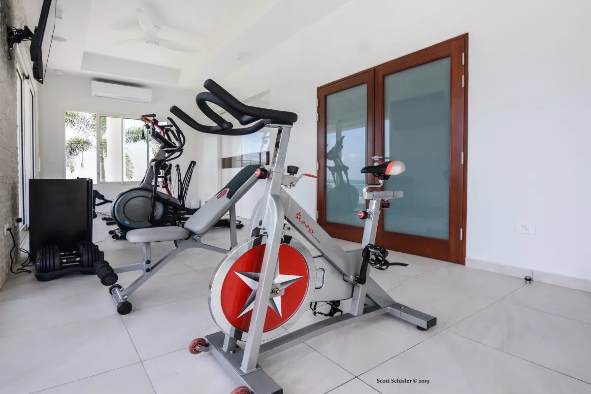 Villa Amalia: Indoor fitness room with stationary bike, weight bench, and exercise machines