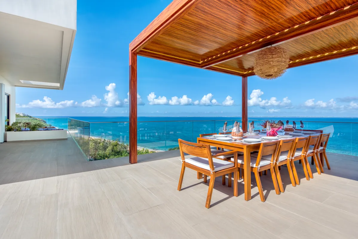 Villa Amandara: Outdoor wooden dining table under a pergola on a terrace overlooking the ocean