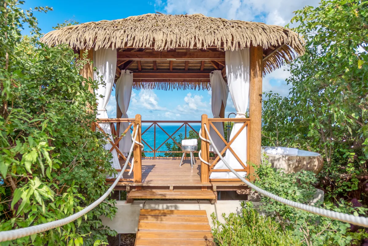 Villa Amandara: Thatched oceanfront gazebo with wooden deck, white curtains, and adjacent stone soaking tub