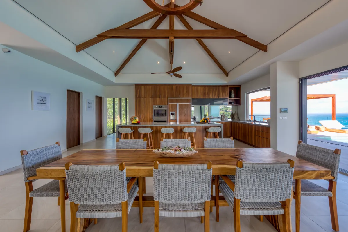 Villa Amandara: Open-plan dining and kitchen area featuring a wooden table under exposed ceiling beams