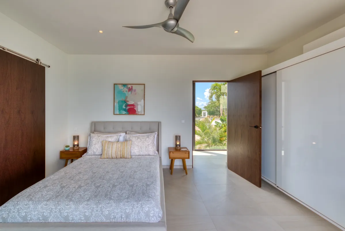 Villa Amandara: Bedroom with a bed, ceiling fan, and open door leading outside to the garden