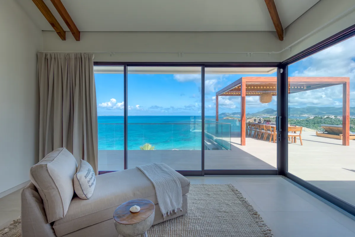 Villa Amandara: Lounge chair by floor-to-ceiling glass doors overlooking a terrace and the sea