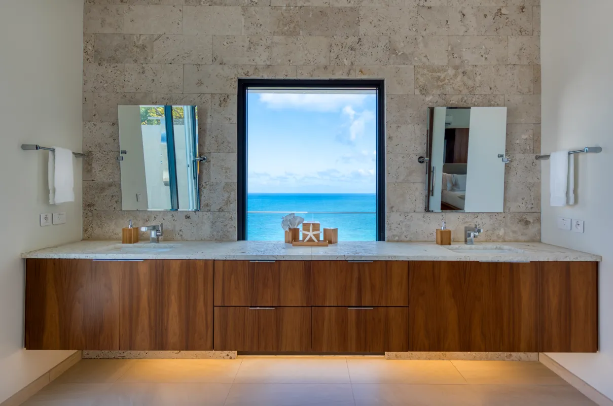 Villa Amandara: Bathroom double vanity with an ocean view through a central window framed by stone tile