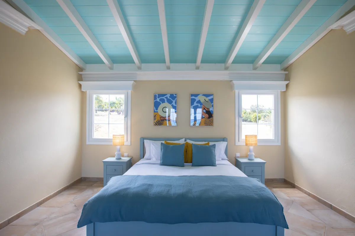 Villa Amber: Bedroom with blue beamed ceiling and blue bedding flanked by nightstands and windows