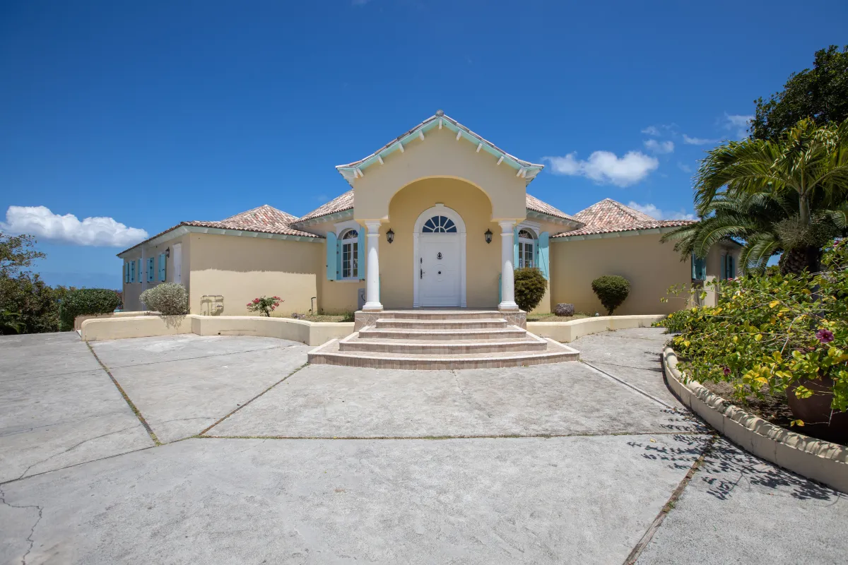 Villa Amber: Front entrance of a yellow villa with an arched doorway, steps, and concrete driveway