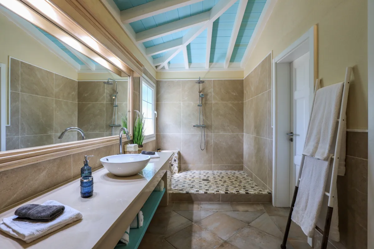 Villa Amber: Bathroom vanity with vessel sink and a tiled walk-in shower under high ceiling beams