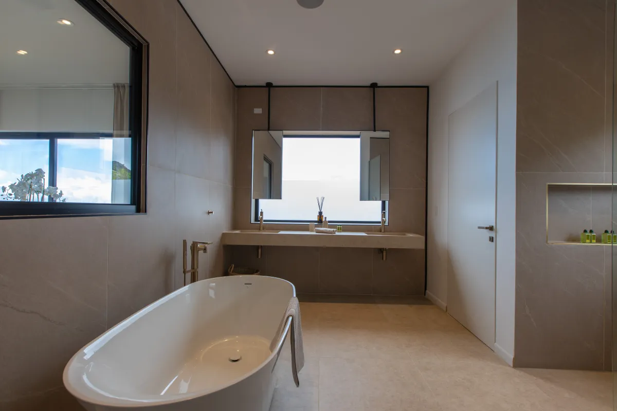 Villa Aqua Dream: Freestanding oval bathtub and double vanity in a modern beige-tiled bathroom