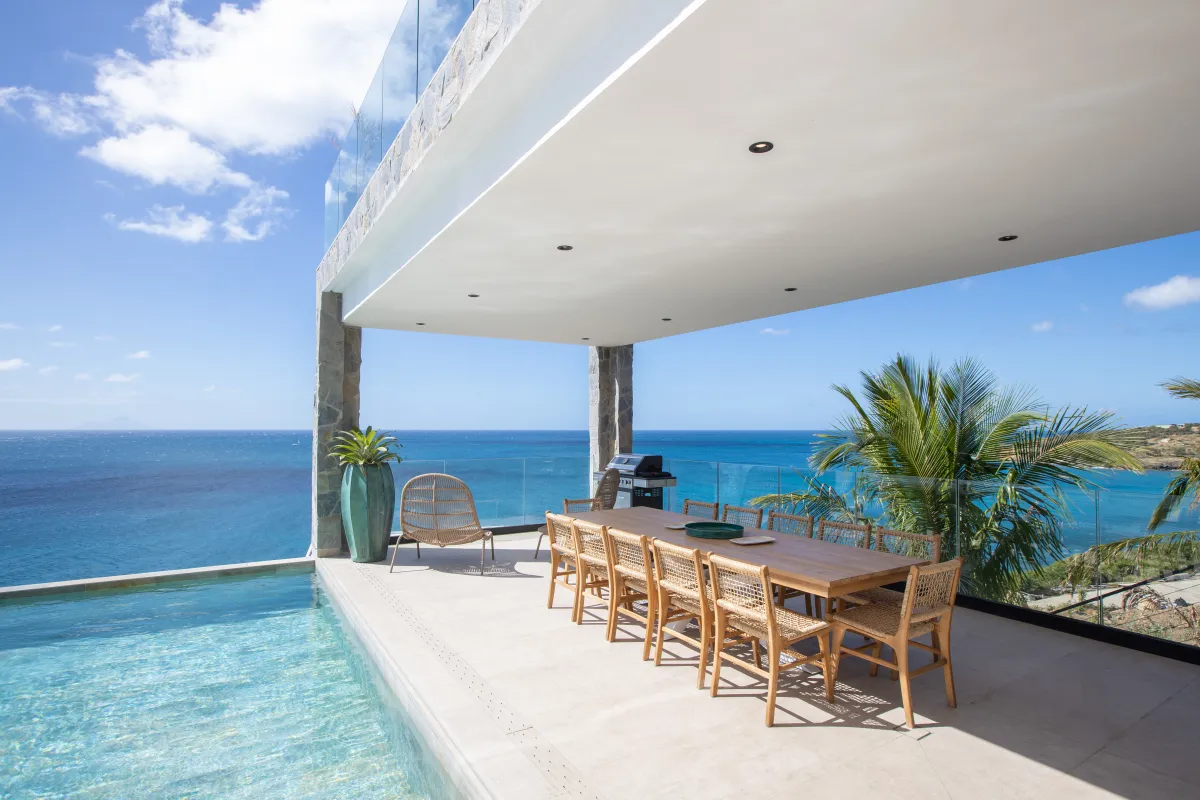 Villa Aqua Dream: Covered terrace with an outdoor dining table beside an infinity pool overlooking the ocean