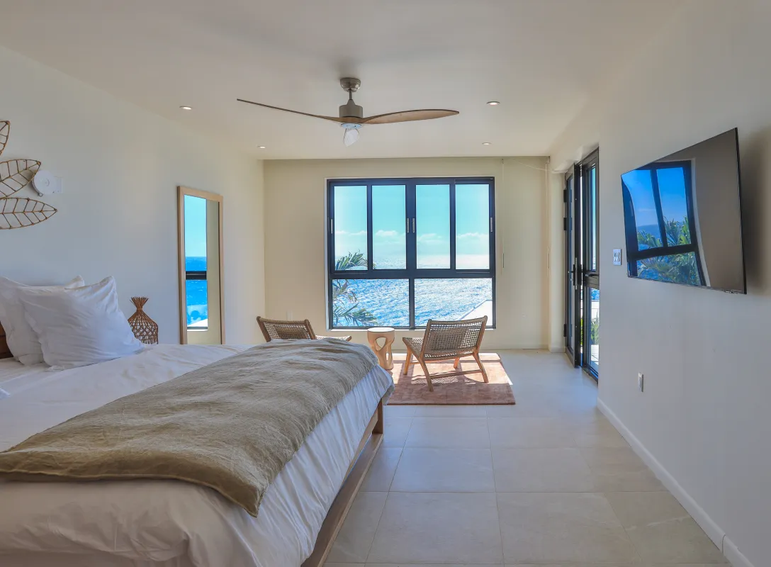 Villa Aqua Dream: Bright bedroom with sea views, seating area, ceiling fan, and wall-mounted television