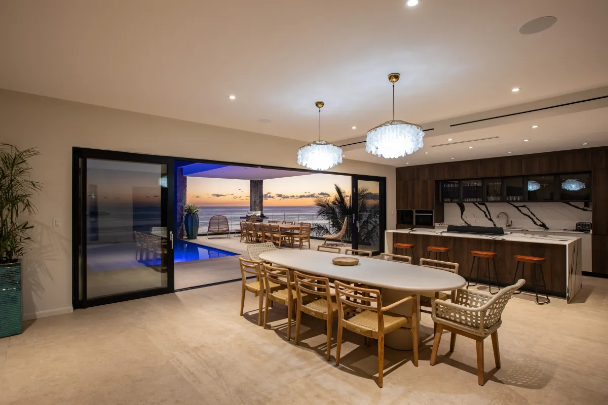 Villa Aqua Dream: Open-plan dining area and kitchen opening to an outdoor terrace and pool at sunset