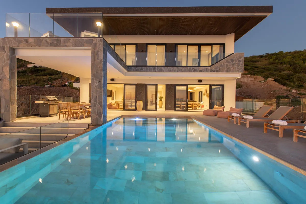 Villa Aqua Vista: Illuminated swimming pool and deck outside a modern two-story villa at dusk