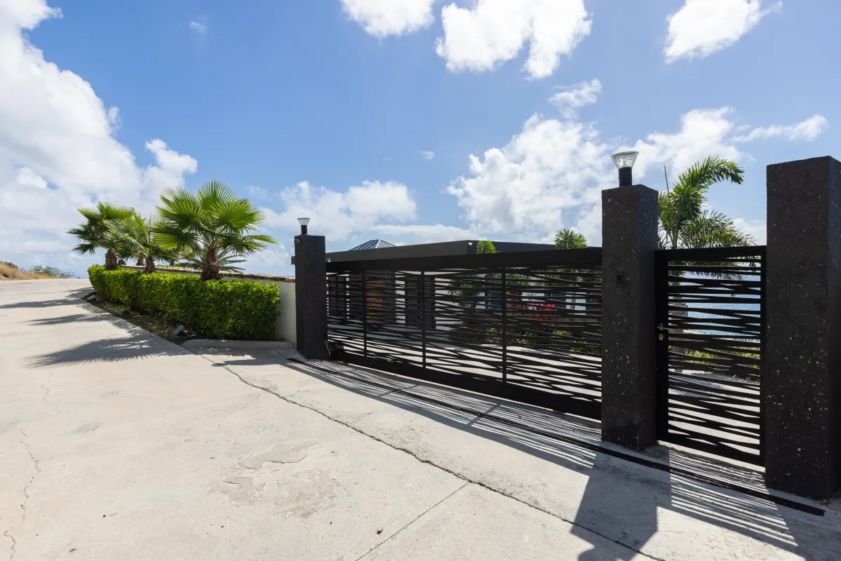 Villa Aqua Vista: Gated entrance to a modern villa with black metal gate and palm trees