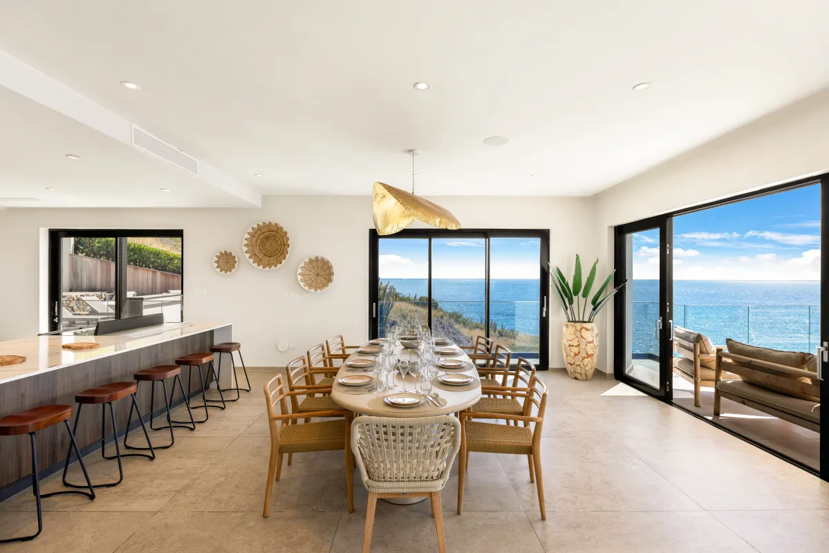 Villa Aqua Vista: Dining table and kitchen island with sliding glass doors opening to ocean views