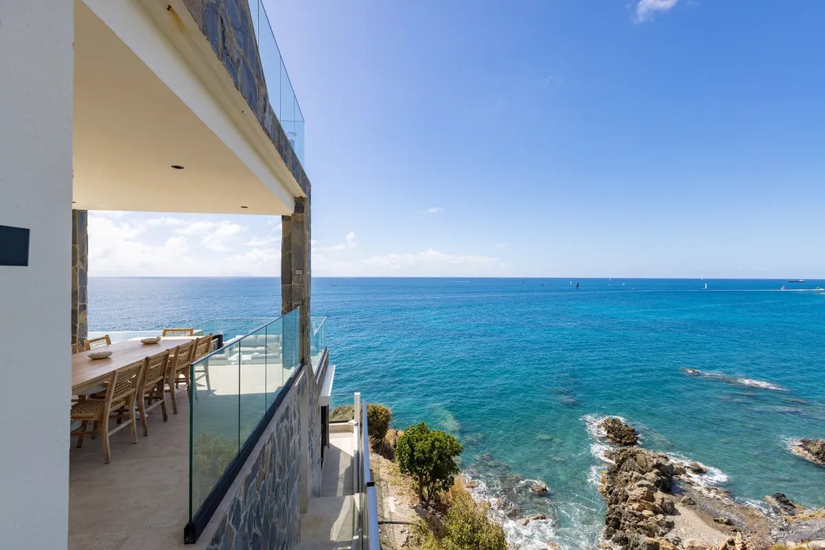 Villa Aqua Vista: Covered terrace with outdoor dining table overlooking the turquoise ocean and rocky coastline