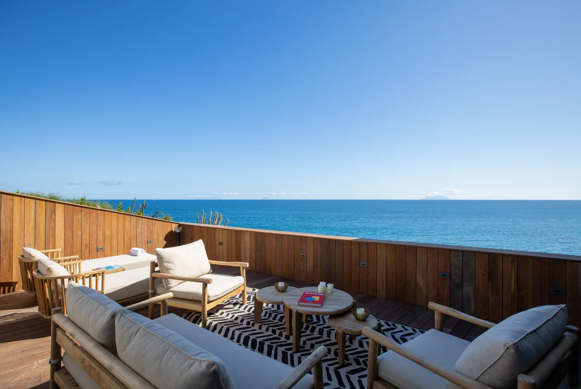 Villa Aqua Vista: Wooden terrace lounge with cushioned seating and expansive ocean views under a clear sky
