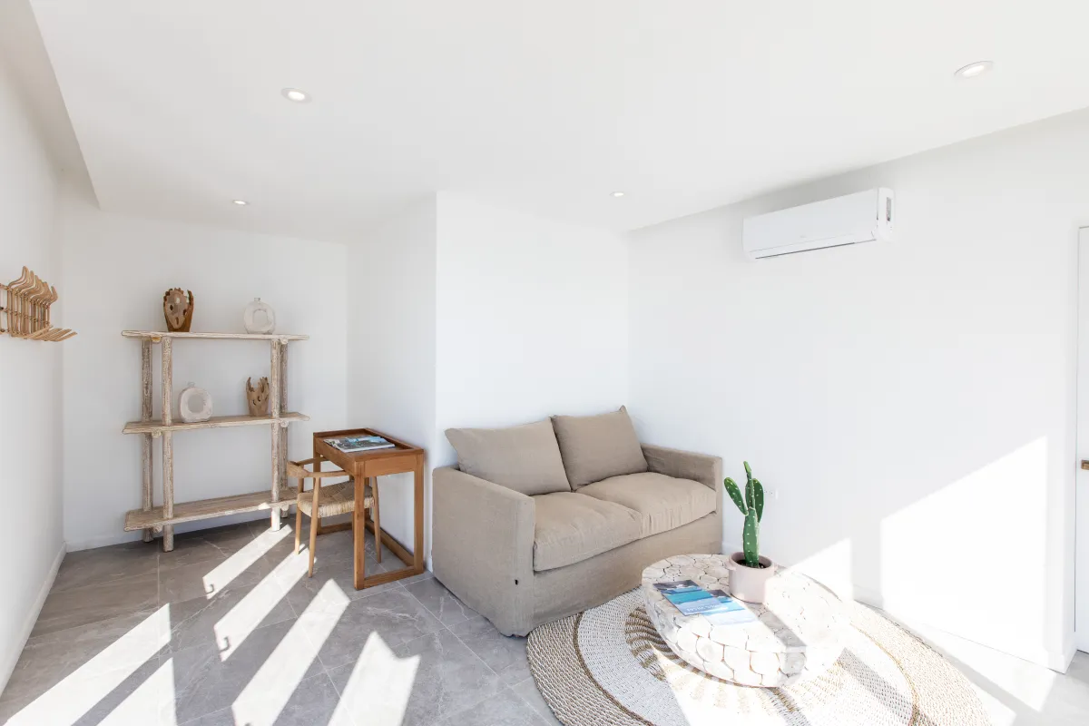 Villa Aqua Vista: Sitting area with a beige sofa, coffee table, and small desk against white walls