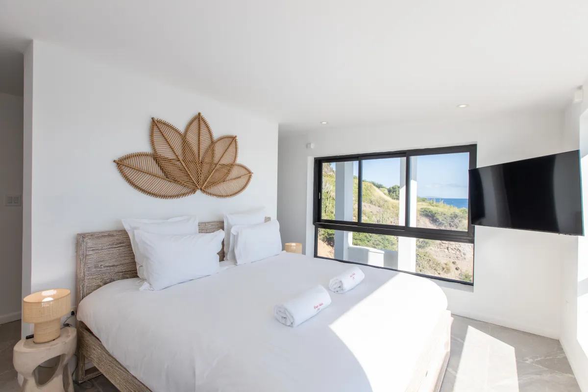 Villa Aqua Vista: Modern bedroom with wooden bed, woven leaf wall art, and scenic window view