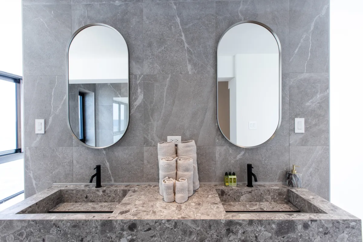 Villa Aqua Vista: Modern bathroom vanity with double stone sinks, black faucets, and oval mirrors