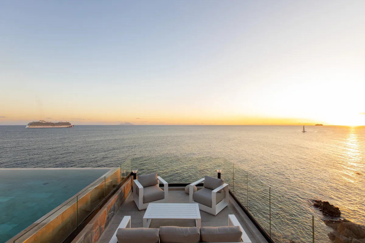 Villa Aqua Vista: Terrace with lounge seating and infinity pool edge overlooking the sea at sunset