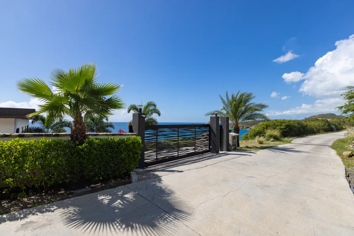 Villa Aqua Vista: Gated property entrance and driveway lined with palm trees overlooking the ocean