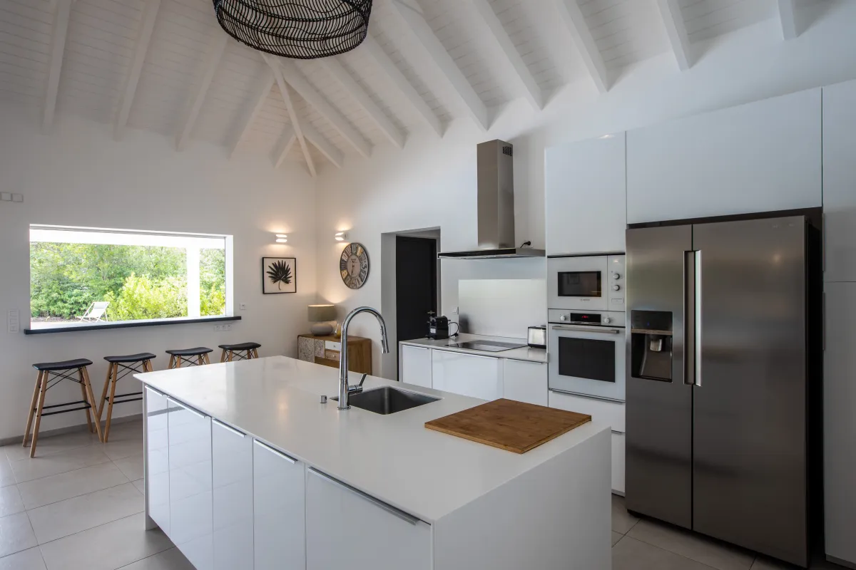 Villa Arawak: Modern kitchen with white island, stainless steel refrigerator, and high vaulted ceiling