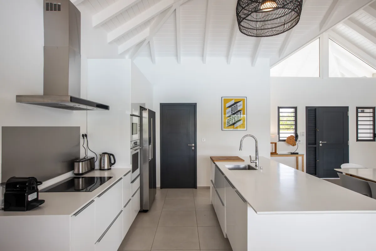 Villa Arawak: Modern white kitchen with central island, stainless steel appliances, and vaulted ceiling