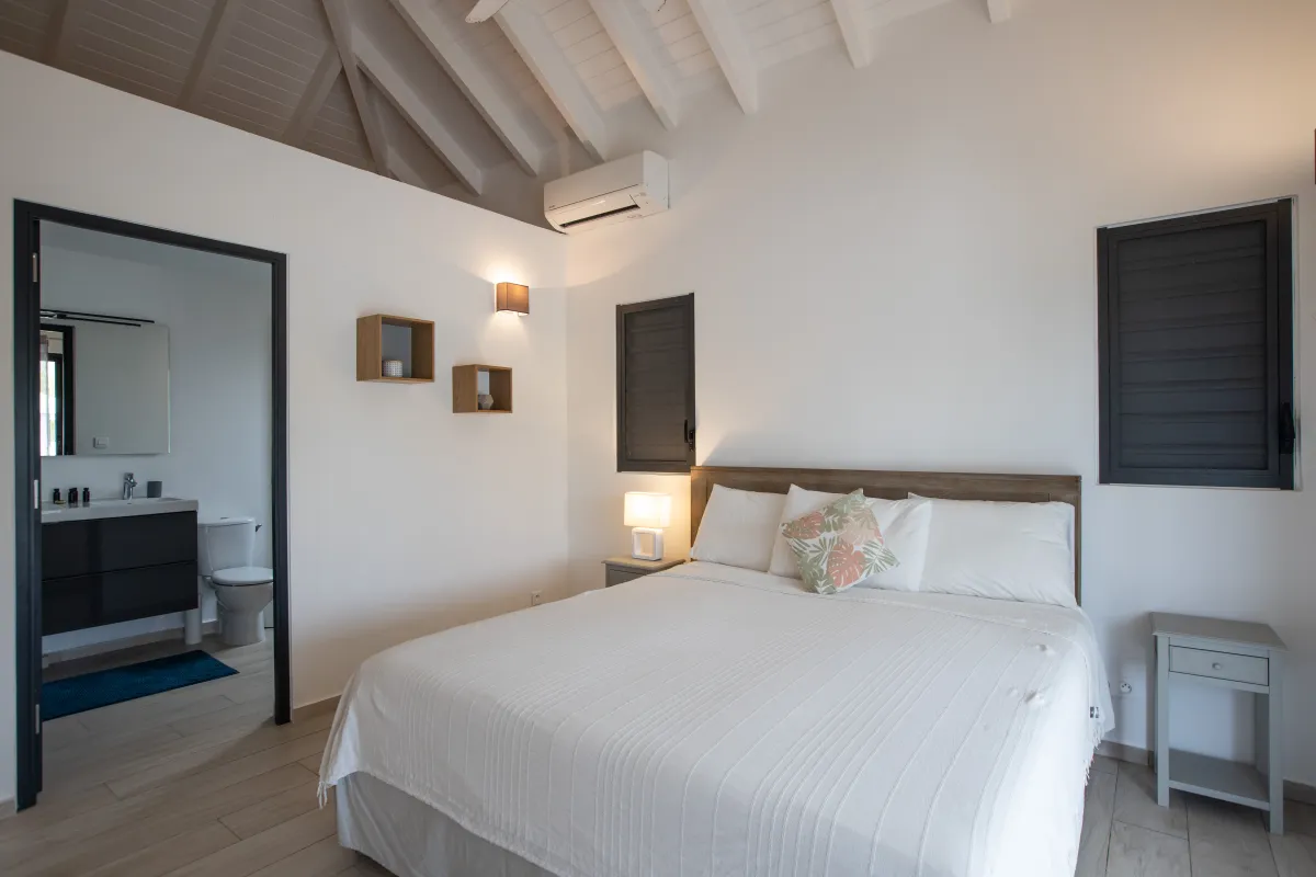Villa Arawak: Bedroom with a white bed, vaulted ceiling, and an open ensuite bathroom