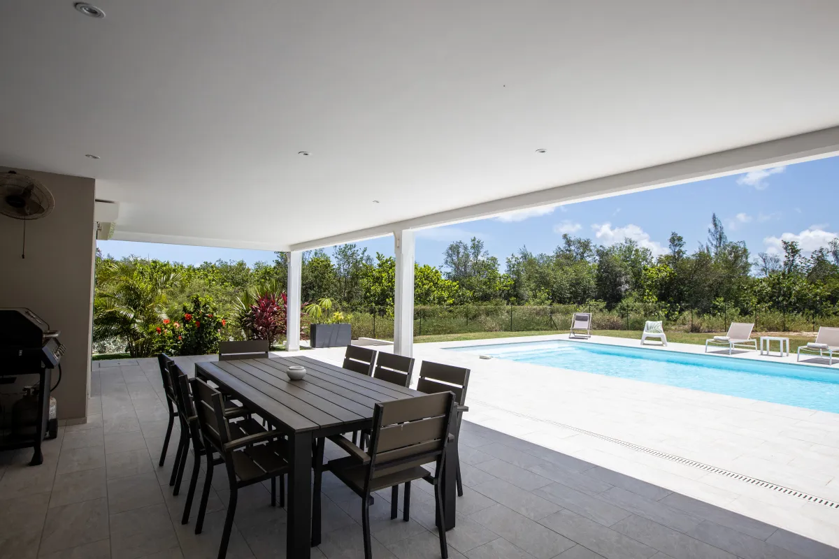 Villa Arawak: Covered terrace with outdoor dining table overlooking a swimming pool and sun loungers