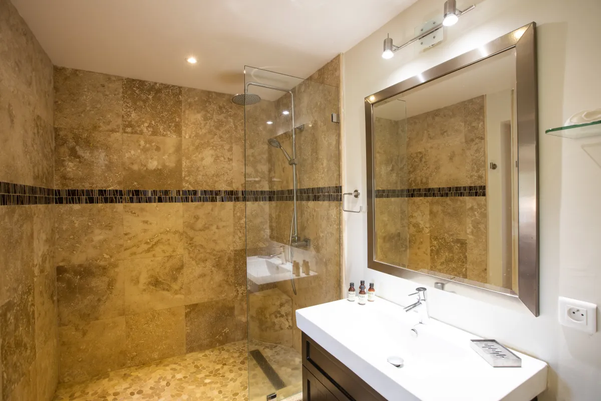 Villa Azur Dream: Bathroom vanity with a large mirror next to a stone-tiled walk-in shower