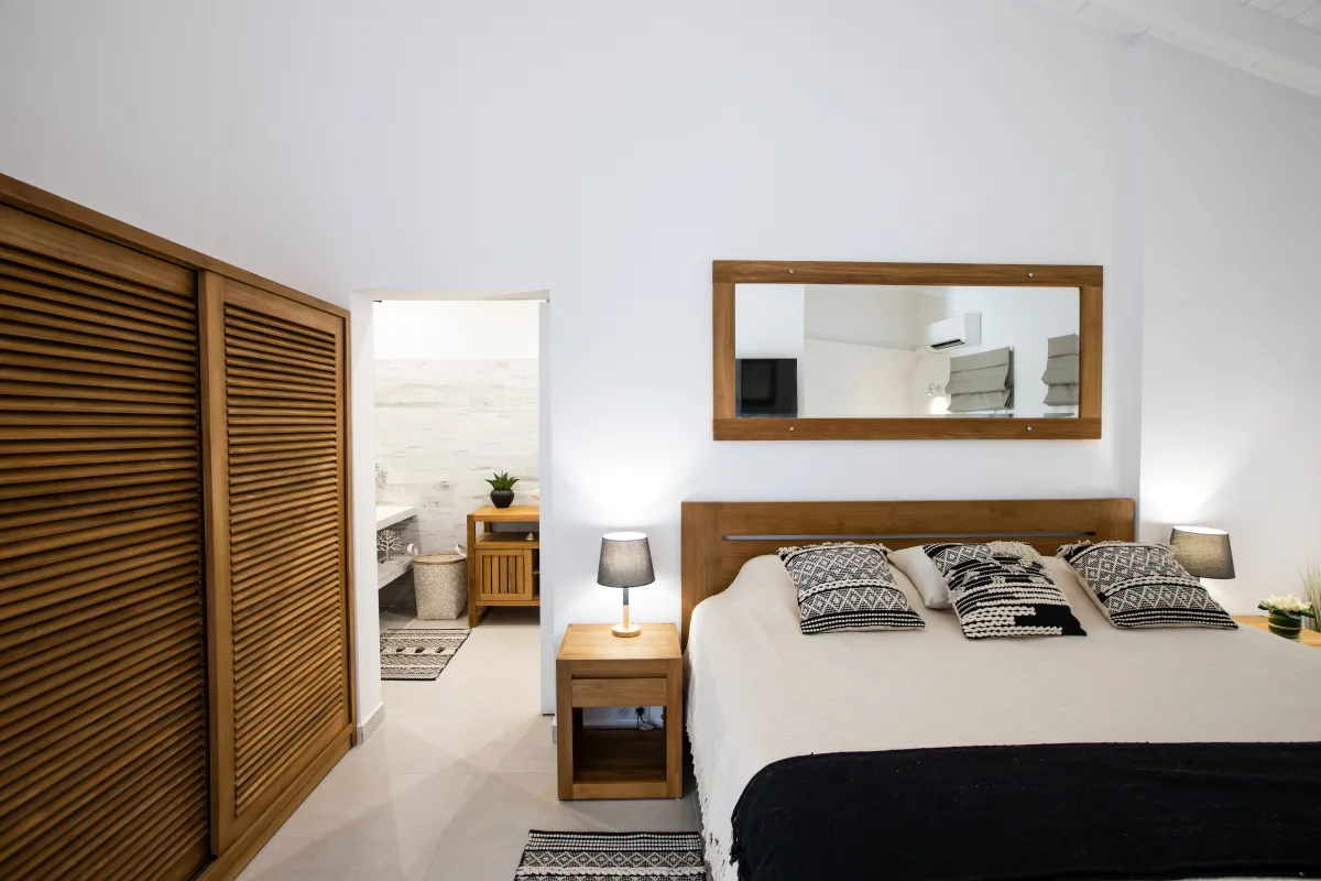 Villa Azur Dream: Bedroom with wooden closet, bed with patterned pillows, and doorway to bathroom