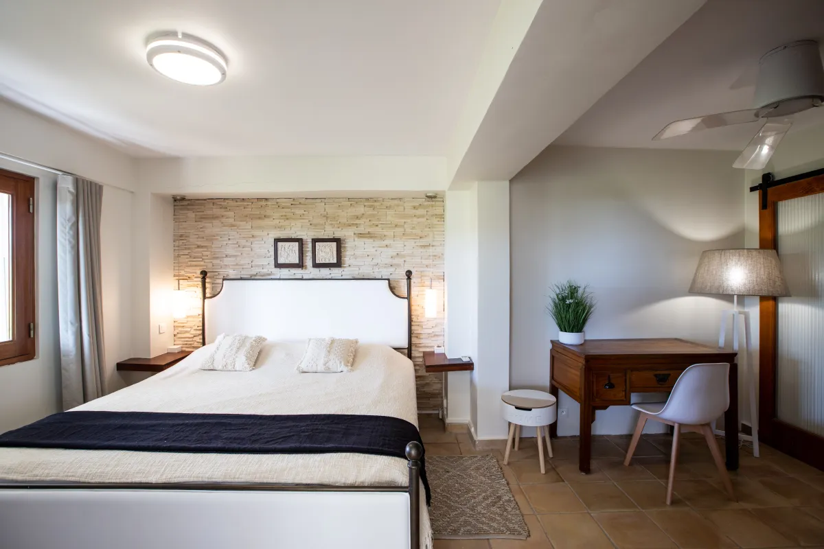 Villa Azur Dream: Bedroom with a king bed, textured stone accent wall, and a wooden work desk