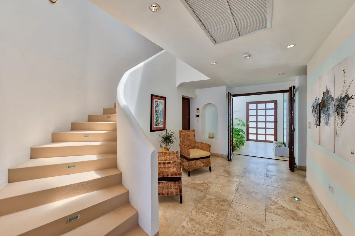 Villa Bahari: Entrance hall with a curved staircase, tile flooring, and wicker armchairs