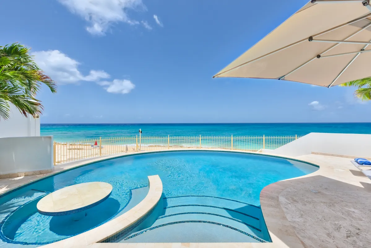 Villa Bahari: Curved swimming pool overlooking a sandy beach and turquoise ocean under a blue sky