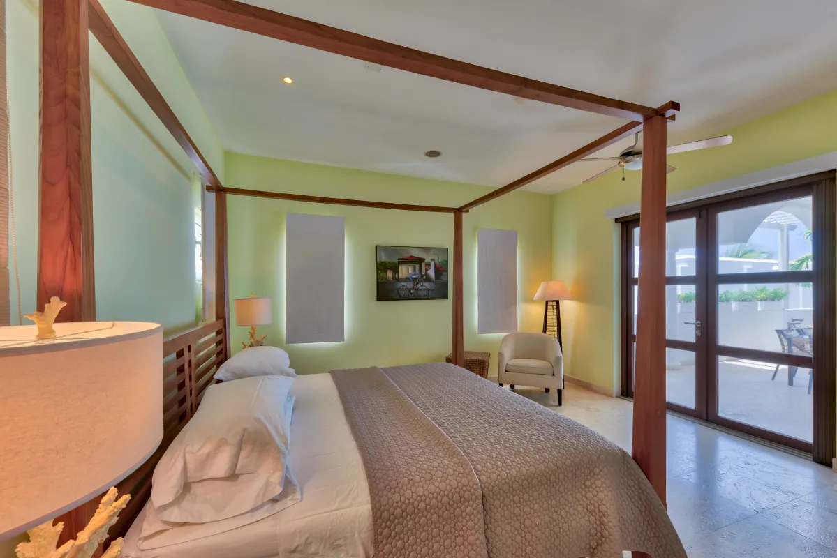 Villa Bahari: Bedroom with a four-poster canopy bed, armchair, and sliding glass doors to a terrace