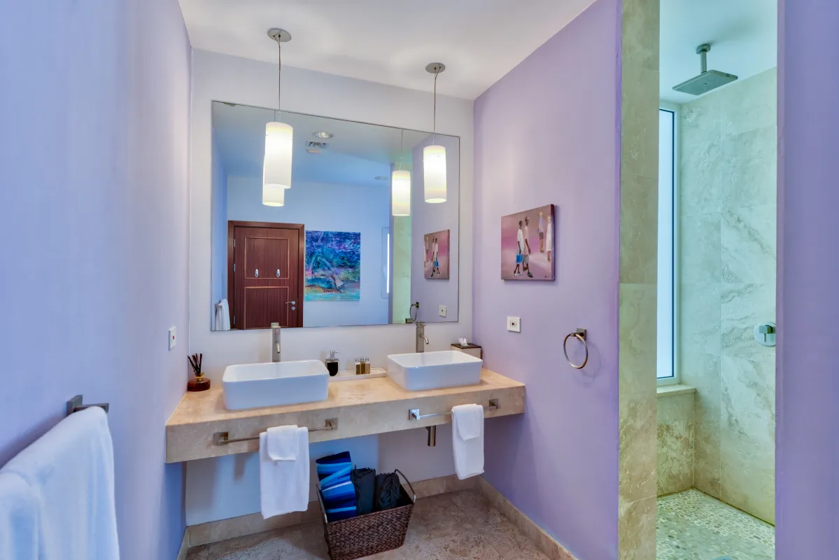 Villa Bahari: Bathroom with double vessel sinks, lavender walls, large mirror, and walk-in shower