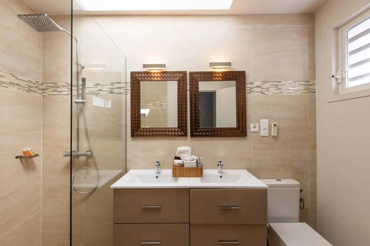 Villa Bahia Blue: Bathroom with a double vanity, twin mirrors, walk-in glass shower, and toilet