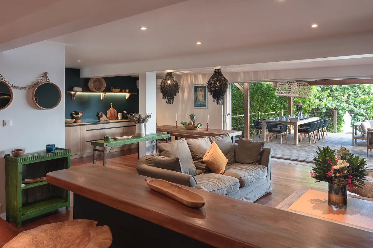 Villa Baltazar: Open-concept living room with sofa and kitchen opening onto a covered outdoor dining deck